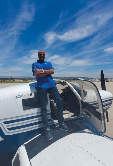 John Howard poses beside an aircraft.