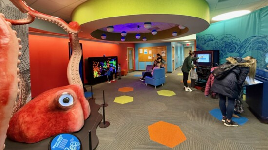 Patrons explore the touch screens of the sea monster exhibit as giant squid tentacles rise from the library floor. Photo: Jennifer Nickels.