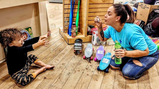 An Olive Branch volunteer plays with a child inside the nonprofit's store. 