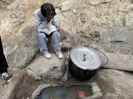 A young boy with the bible we gave him, reading about the wellspring of life while sitting next to the only well in his town.