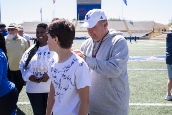 Coach Kevin Wilson signs a young mans shirt at the Tulsa Football Springfest. Photo provided.