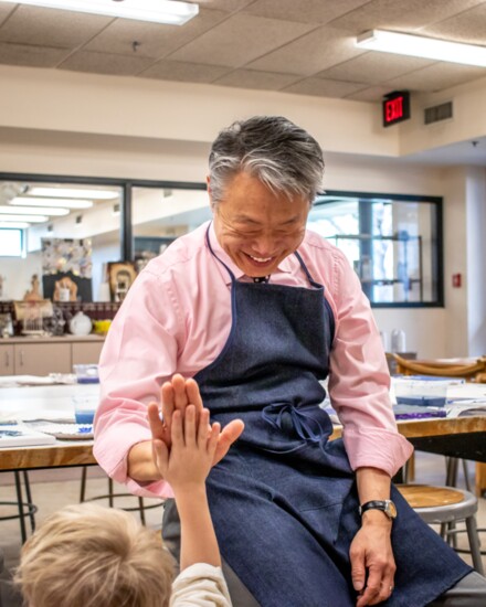 Art teacher Byron Shen smiles as he high-fives a student. 