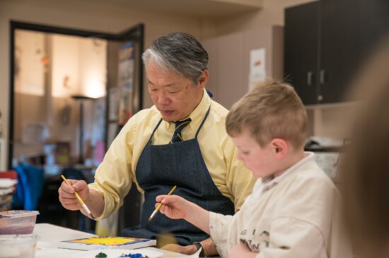 Art teacher Byron Shen paints with a student. 