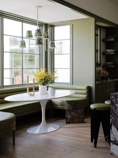 A banquette in channel - tufted fabric and an oval Tulip Table complete the kitchen breakfast nook.