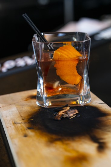 El Viejo, a smoked Tequila Old-Fashioned is made by torching cherrywood chips, smoking the glass with the orange peel, and finishing with a Luxardo cherry.