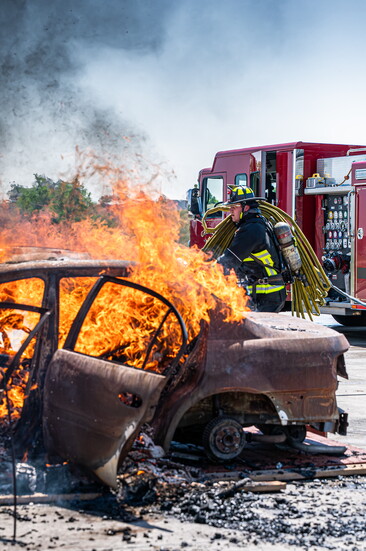Firefighter deploying a hose line during a live burn training