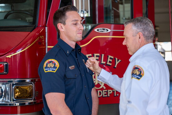 Fire Chief Kuznik performs a symbolic badge pinning during the field promotional ceremony for Lieutenant F. Anguiano