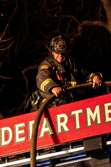 Lieutenant M. Flatt performs firefighting duties on the aerial ladder during a structure fire in Greeley
