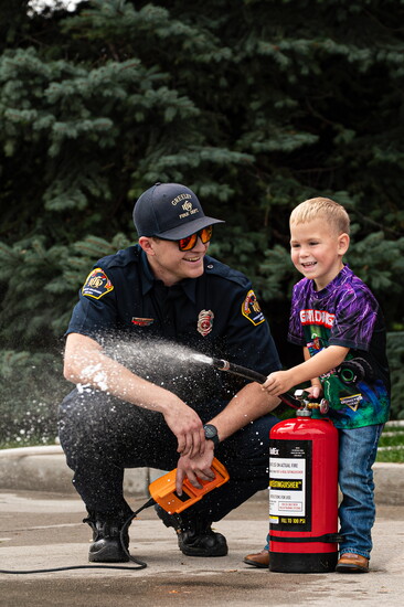 Firefighter B. Garrot having fun with kids putting out a fire with a fire extinguisher during the 2025 Greeley Fire Station 5 Open House