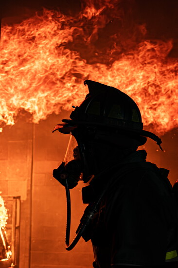 A Greeley firefighter walks in front of flames during a live burn training in 2025