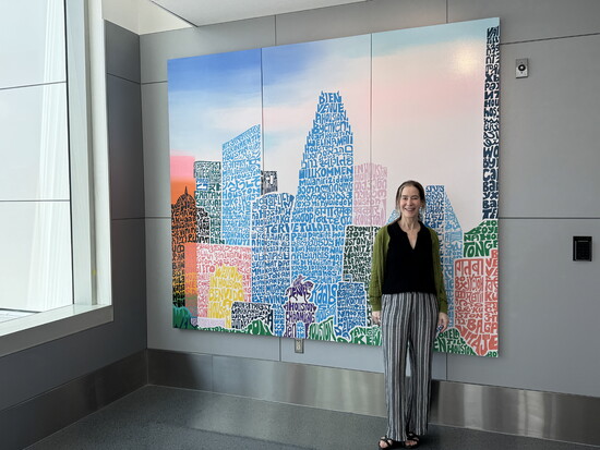 Marlo Saucedo stands beside “Welcome to Houston” at IAH Houston George Bush Intercontinental Airport Gate D-5, a work by Saucedo and Leslie Gaworecki.
