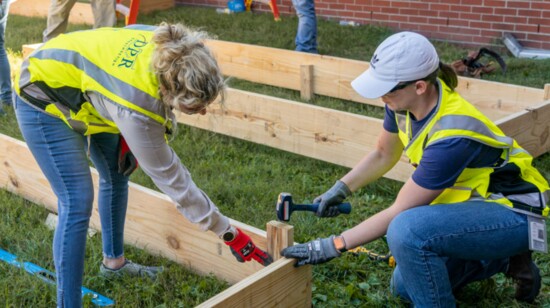 Volunteers piece together frameworks for new garden beds.