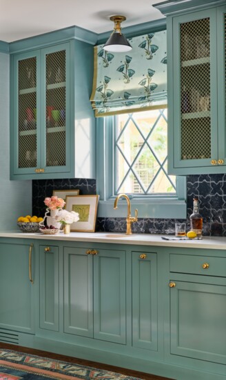 Benjamin Moore’s Fort Pierce Green lacquers the bar. Brass hardware is by Rejuvenation, and the dark blue tile backsplash is from Art of Stone.