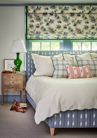 The primary bedroom is layered with fabrics in a variety of prints and colors. Roman shade fabric is by Décors Barbares. Headboard fabric is Colefax and Fowler.