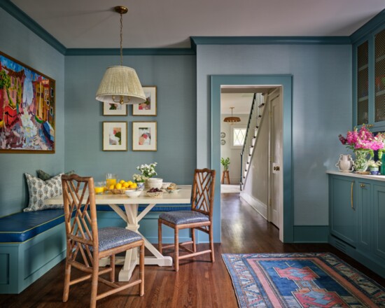 The painting over the breakfast nook was restored and reframed after it survived the fire. The banquette is upholstered in Kravet vinyl.  