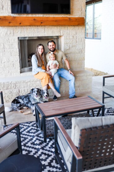 Homeowners Isaac and Kelly Spear, their baby wnd their dogs take time out to enjoy the covered porch area of their new home.