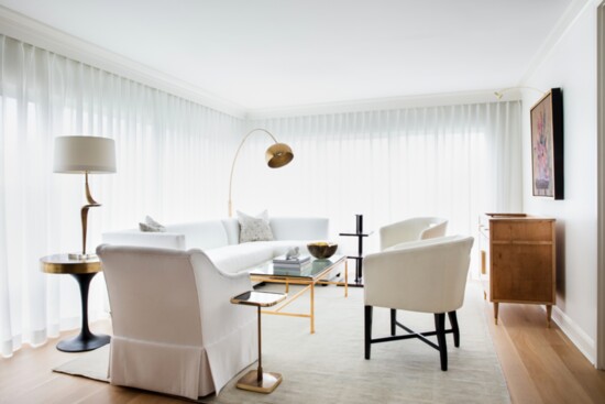 Cream leather chairs add updated style to white linen sectional sofa.