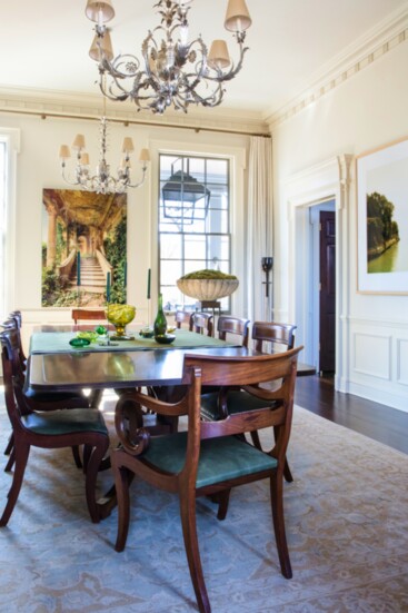 Double chandeliers and dramatic art set the scene for a family’s dining room.