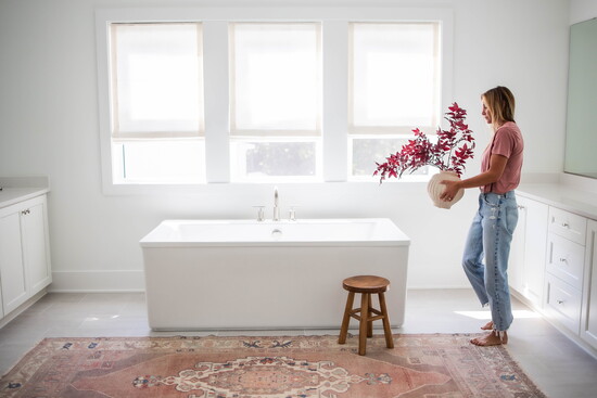 A freestanding tub bathed in natural light becomes a retreat within the home. Large windows and soft finishes help achieve a spa-like feel with minimal fuss.