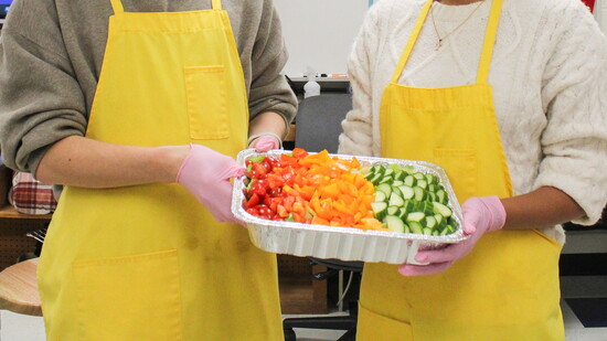 Students cooking for a gluten-free family show off their rainbow salad