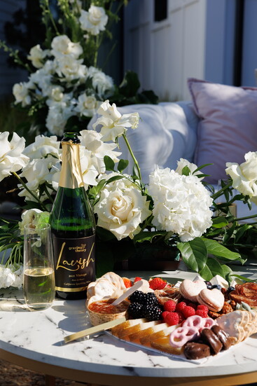 The "Show Me the Love" heart-shaped charcuterie board, paired with a bottle of Lavish champagne, provided by Grazing Theory.