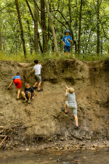 Countryside Montessori Forest School students climb up a hill on the side of the creek.