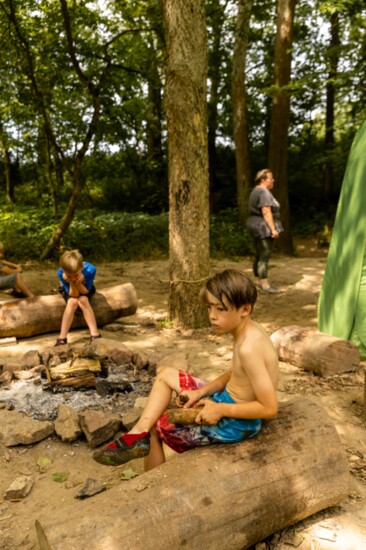 Liam Anderson, right, whittles a piece of wood with a knife. 