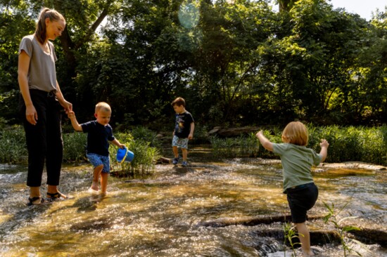 Mothers guide their toddlers through Line Creek during a meet-up for the North KC Forest Playgroup.