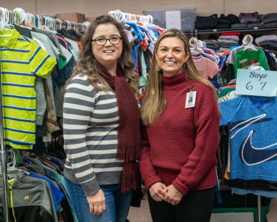 Assistant Director of Schools for Student Support Katie Brown and Family Resource Center Director Cathy Graff pose in front of a clothing rack.