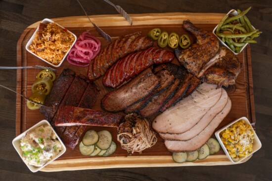 A Grazing Board filled with brisket, ribs, chicken, sausage, and a choice of sides.