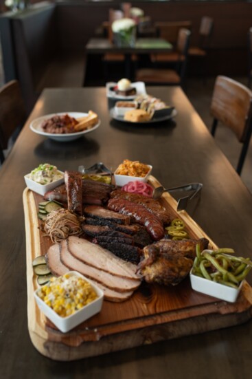 A Grazing Board filled with brisket, ribs, chicken, sausage, and a choice of sides. 