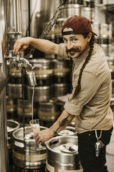 Kyle Jukes, head brewer, pulls a fresh glass of beer from one of his large serving tanks