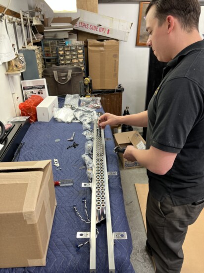 Sales manager Tim Schaeffer works on a piston rail system for a player piano device. Each key gets its own piston to make the hammer strike the string.