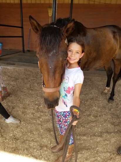 Felicity poses by the horse she learned to ride during her week at Camp Cadence.