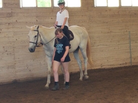 Young volunteers assist equally-young riders just learning about horseback riding.