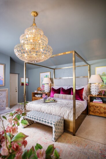 A four-poster king bed framed in brushed brass is complemented by elegant nightstands in olive ash veneer. 