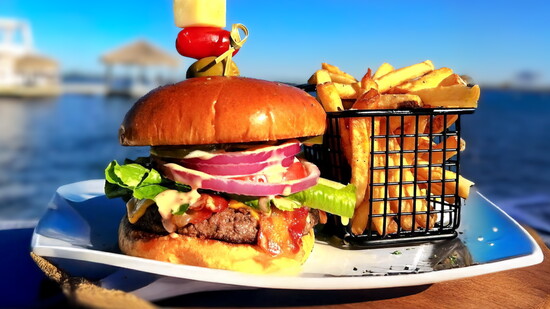 Stacked "Bloody Mary Burger" with shrimp skewer and fries, enjoyed right by the water.