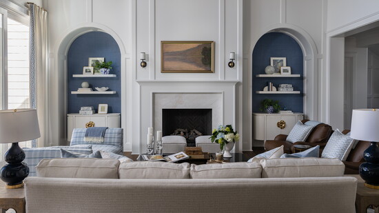 The living room features trim detailing by Ellis Reid Millworks. The sconces are by Visual Comfort. Two white Currey & Company cabinets are