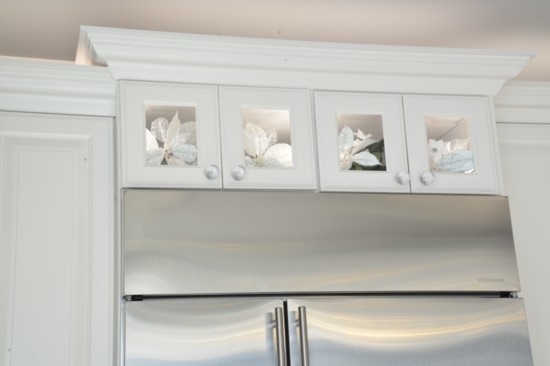 Beveled glass panes were used in the over-refrigerator cabinets rather than wood to keep the look light.