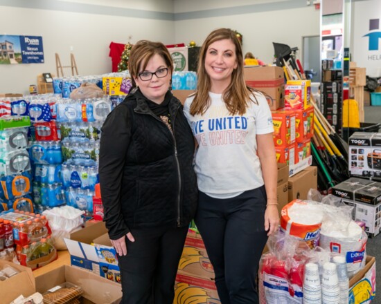 Chamber CEO Kathleen Hawkins and United Way CEO Erin Birch stand amid an assortment of cleaning supplies.