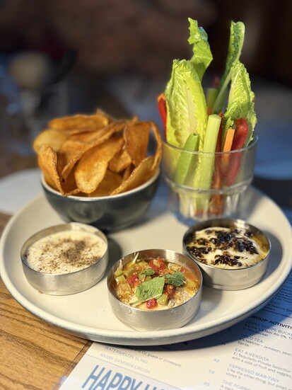 Chips, Dips & Crudités: Hummus, blue cheese and parmesan dip, truffle honey ranch, seasoned chips, carrots, celery, and red peppers.