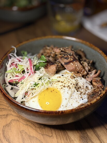 BBQ Rice Bowl—Korean BBQ-style pork, ginger, garlic, soy sauce, fried egg, pickled onion, cabbage, cilantro, and spicy mayo.