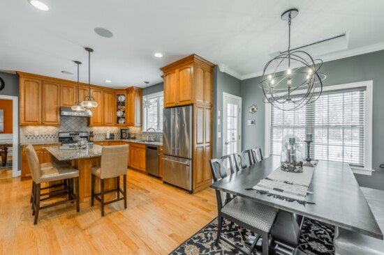 The kitchen in the home at 29 Hampton Court features granite counters, wood floors and custom light fixtures. It opens up to a dining area. 