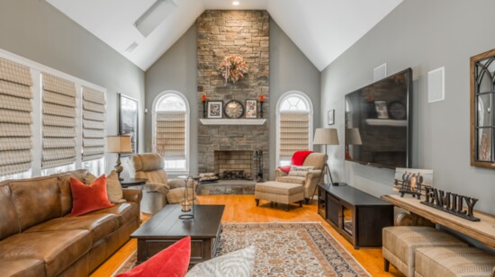 The family room in the home has a floor-to ceiling fieldstone fireplace and wood floors. 