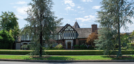 A Tudor Revival in Los Cerritos featuring steep rooflines, exposed half-timbering, and diamond-pane glass that creates a charming contrast in suburban settings.