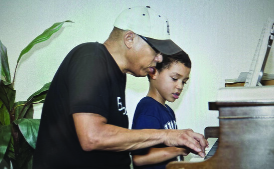 Charles, Alex's father showing him how to play piano at a young age. 