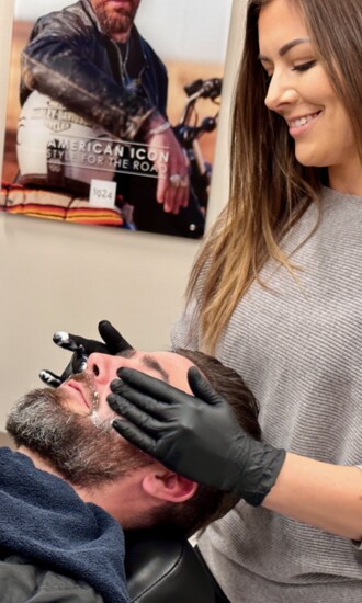 Emily prepping customer Josh for his straight-razor beard trim and shave