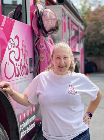 A breast cancer survivor and volunteer with For 3 Sisters poses with Vicky the pink fire truck.