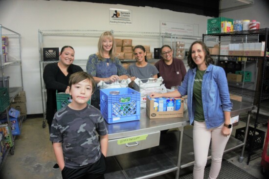 The Loudoun Education Foundation team, joined by a student volunteer, packs meal bags for their Backpack Coalition program. Photo Kirslyn Schell-Smith