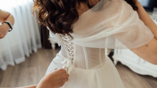 Person helping bride with the dress.